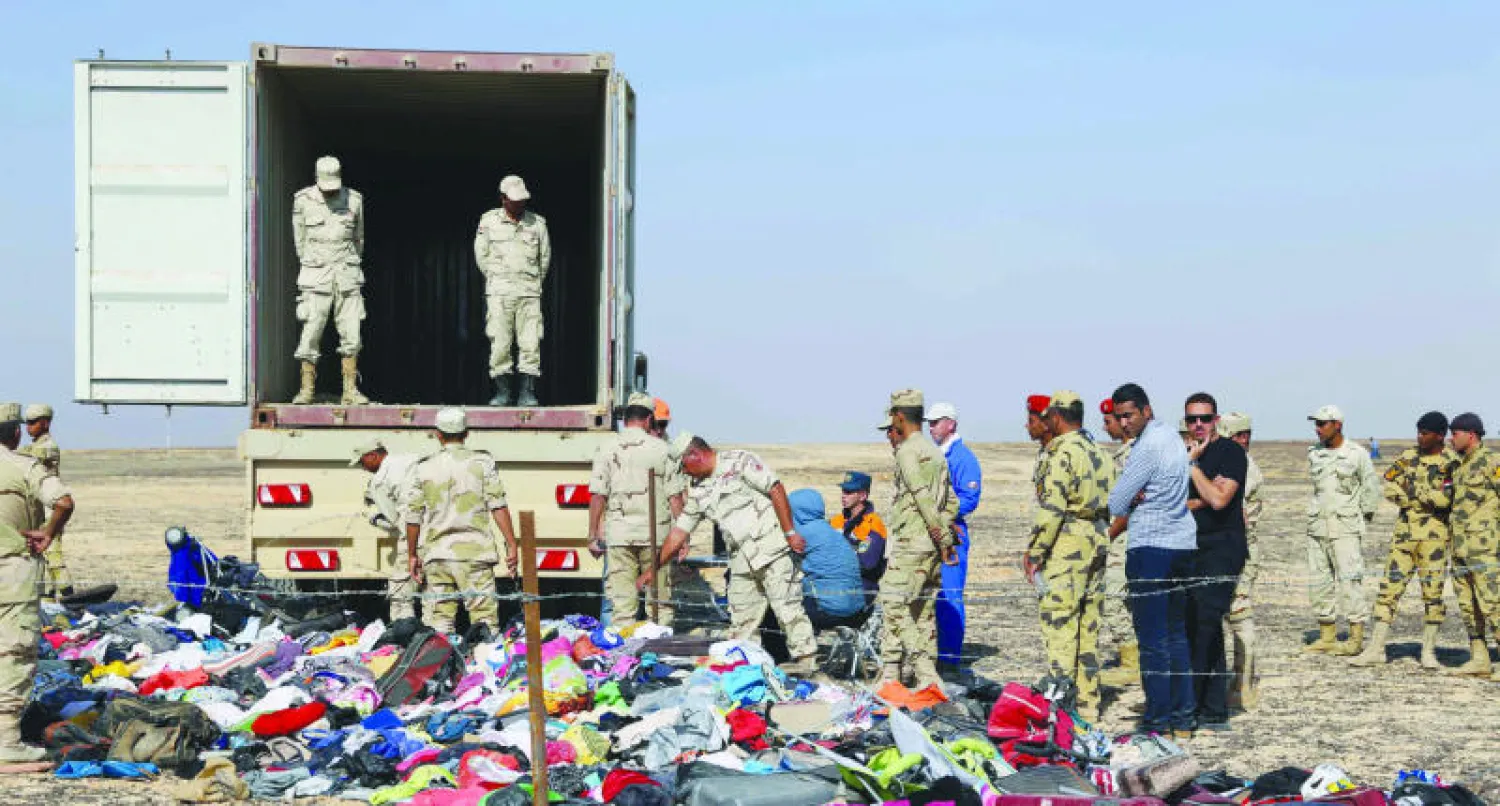 مسؤولون مصريون وروس يتفقدون ما تبقى من حقائب ضحايا الطائرة الروسية التي سقطت بالقرب من مدينة العريش  (أ.ف.ب)