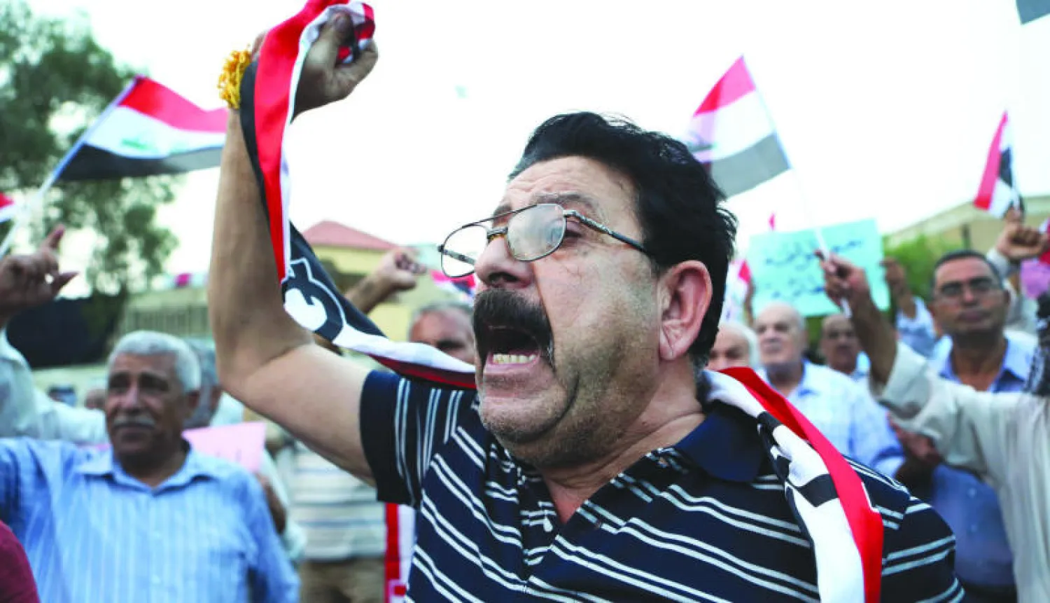 عراقيون مناهضون للحكومة يرفعون الأعلام العراقية خلال مظاهرة ضد الفساد وتردي الخدمات في البصرة  (ا.ف. ب)