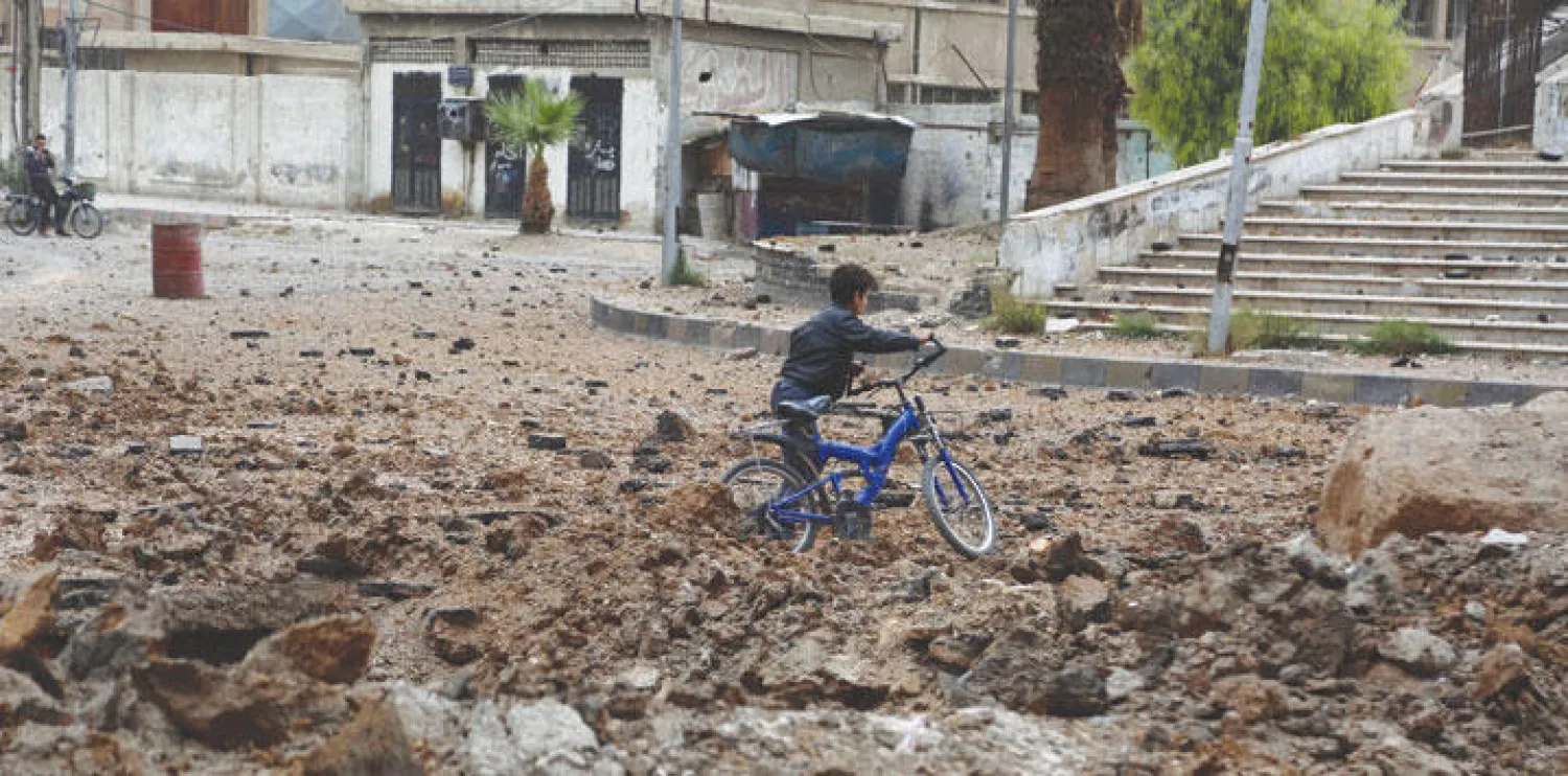 طفل سوري يسير وسط الركام أمس بعد غارة جوية شنها طيران النظام على مدينة دوما قرب العاصمة السورية دمشق (إ.ب.أ)