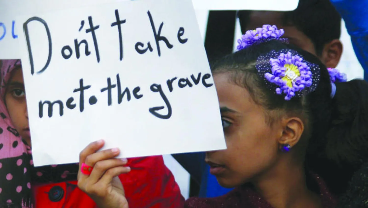 فتاة تحمل لافتة تقول «لا تأخذني إلى القبر» خلال مظاهرة احتجاج في تعز ضد الحصار المفروض على  المدينة (رويترز)