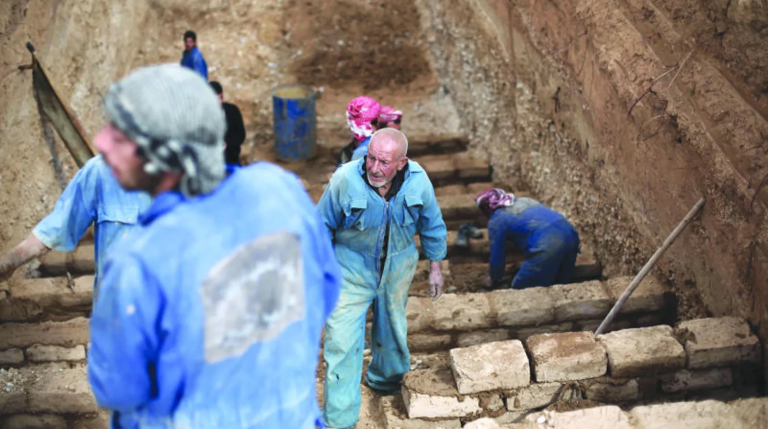 عمال يحفرون قبورا في دوما شرق دمشق أمس لاستيعاب العدد المتزايد من ضحايا قصف طائرات النظام (أ.ف.ب)