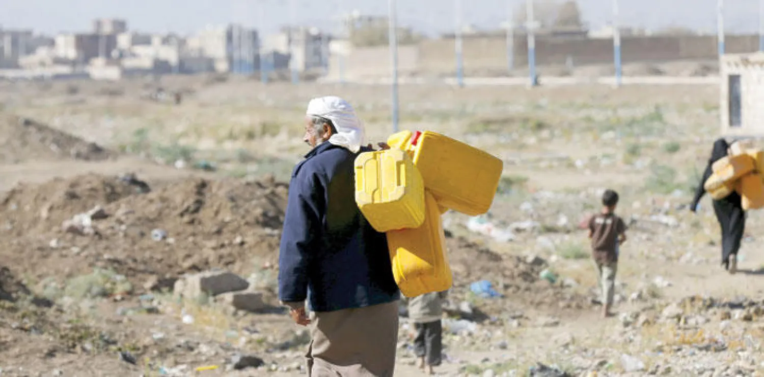 يمني يحمل غالونات بلاستيكية لملئها من بئر بسبب نقص المياه الصالحة للشرب في العاصمة صنعاء أمس (رويترز)
