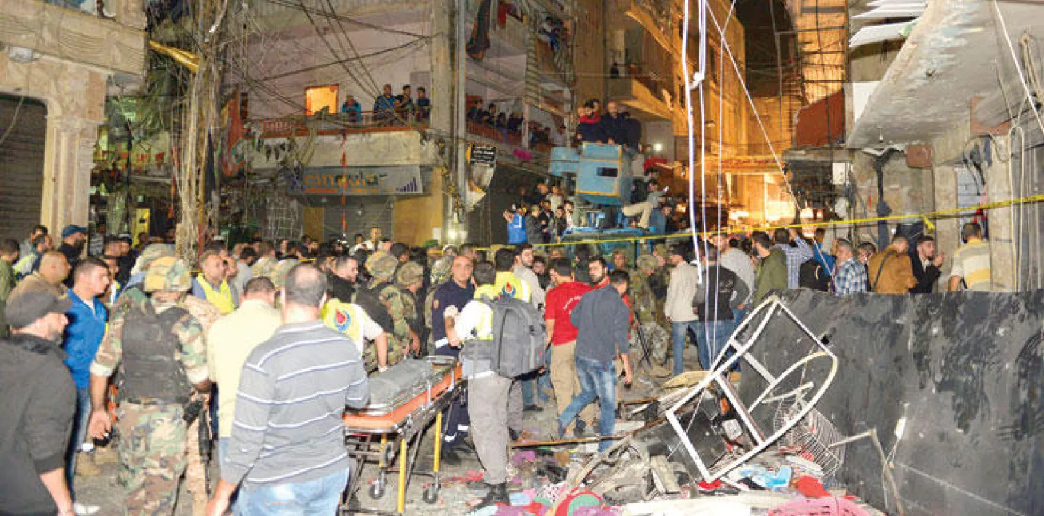 عناصر أمن وسكان يعاينون آثار الدمار الناجم عن التفجير المزدوج في منطقة برج البراجنة ببيروت مساء أمس (إ.ب.أ)