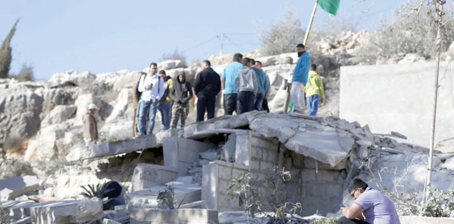 فلسطينيون يعاينون ركام بيت عائلة فلسطيني قتل إسرائيليا نسفته قوات الاحتلال في بلدة سلواد بالضفة أمس (أ.ف.ب)