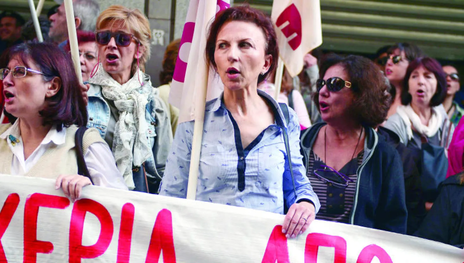 يونانيات يشاركن في مظاهرة أمام وزارة المالية في أثينا أمس قبل بدء التصويت على إجراءات التقشف الجديدة (أ.ف.ب)