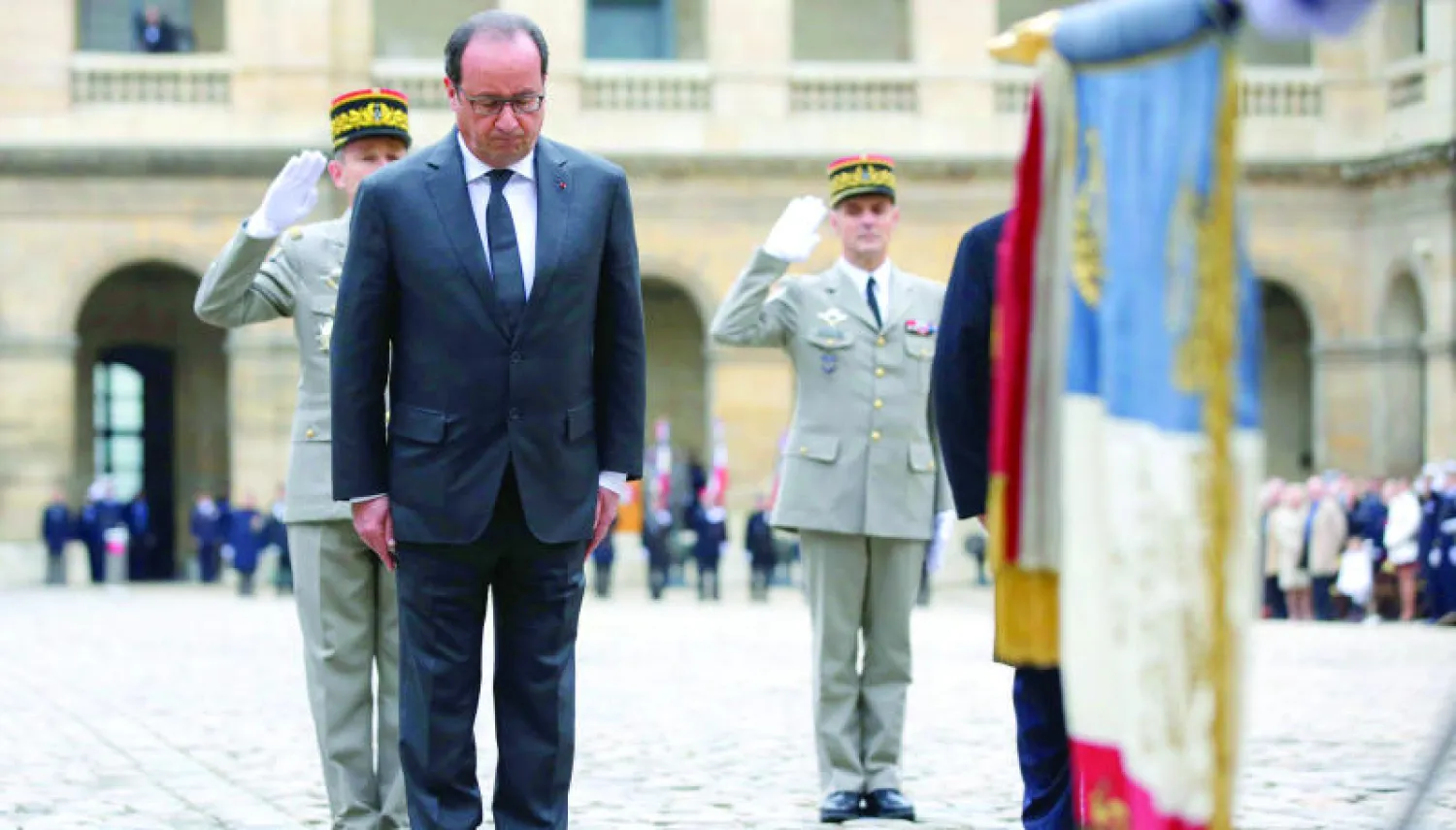 الرئيس الفرنسي فرنسوا هولاند يقف أمام العلم الفرنسي حداداً على ضحايا الهجمات الإرهابية الأخيرة في فندق ليزانفاليد بباريس أمس (إ.ب.أ)