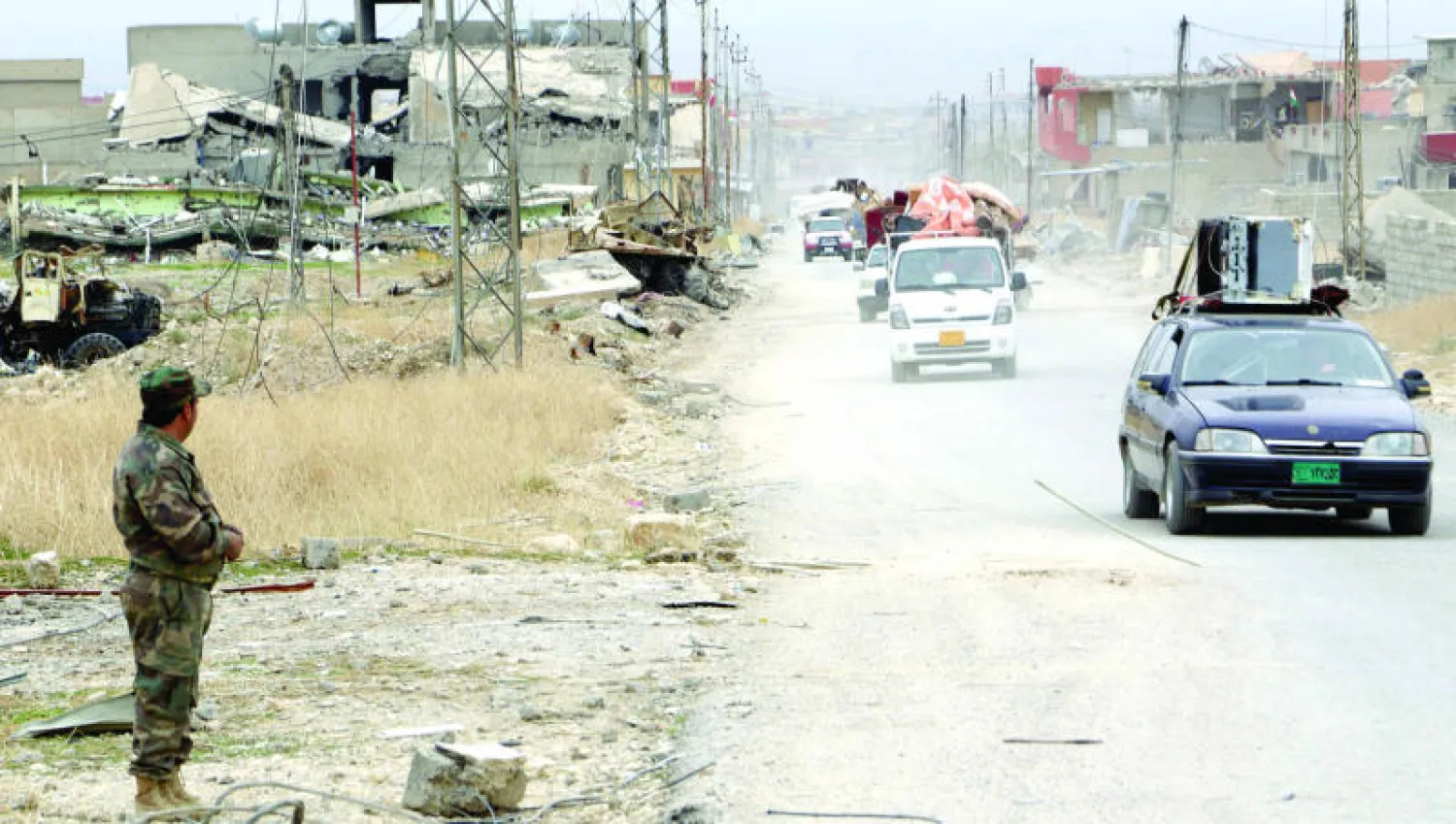 مقاتل من البيشمركة يراقب سيارات مواطنين يعودون قبل أيام إلى بيوتهم في سنجار بعد تحريرها من «داعش» (رويترز)