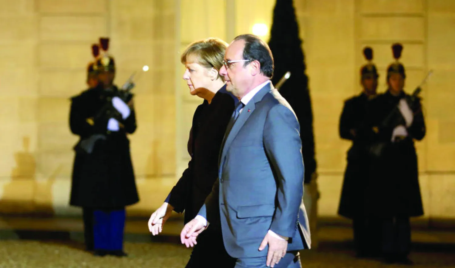 الرئيس الفرنسي فرنسوا هولاند يصل إلى قصر الإليزيه مع المستشارة الألمانية أنجيلا ميركل أمس (رويترز)