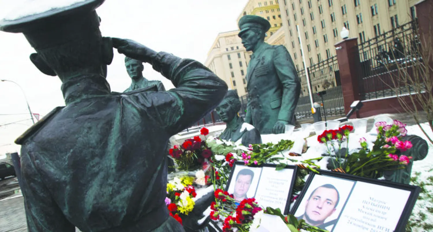 نصب تذكاري لضباط الجيش السوفياتي وقد وضعت عليه صورتا الطيارين الروسين والزهور وطائرة ورقية  خارج مقر قيادة الأركان العامة الروسية في موسكو أمس (ا.ف.ب)