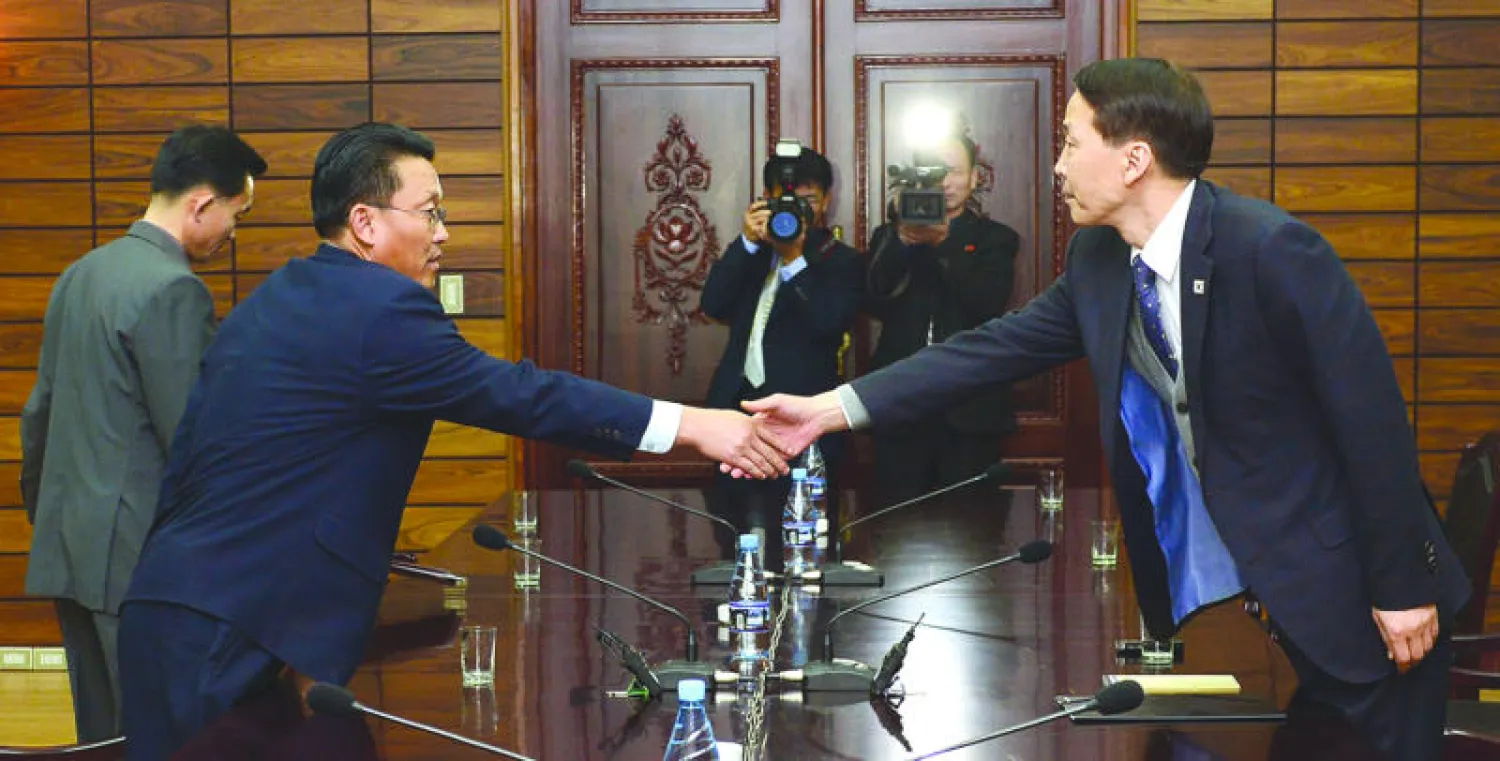 رئيس الوفد الكوري الجنوبي كي كي وونغ يصافح رئيس وفد كوريا الشمالية وانغ شول  خلال مباحثاتهما أمس في بلدة بانمونغون (أ.ب)