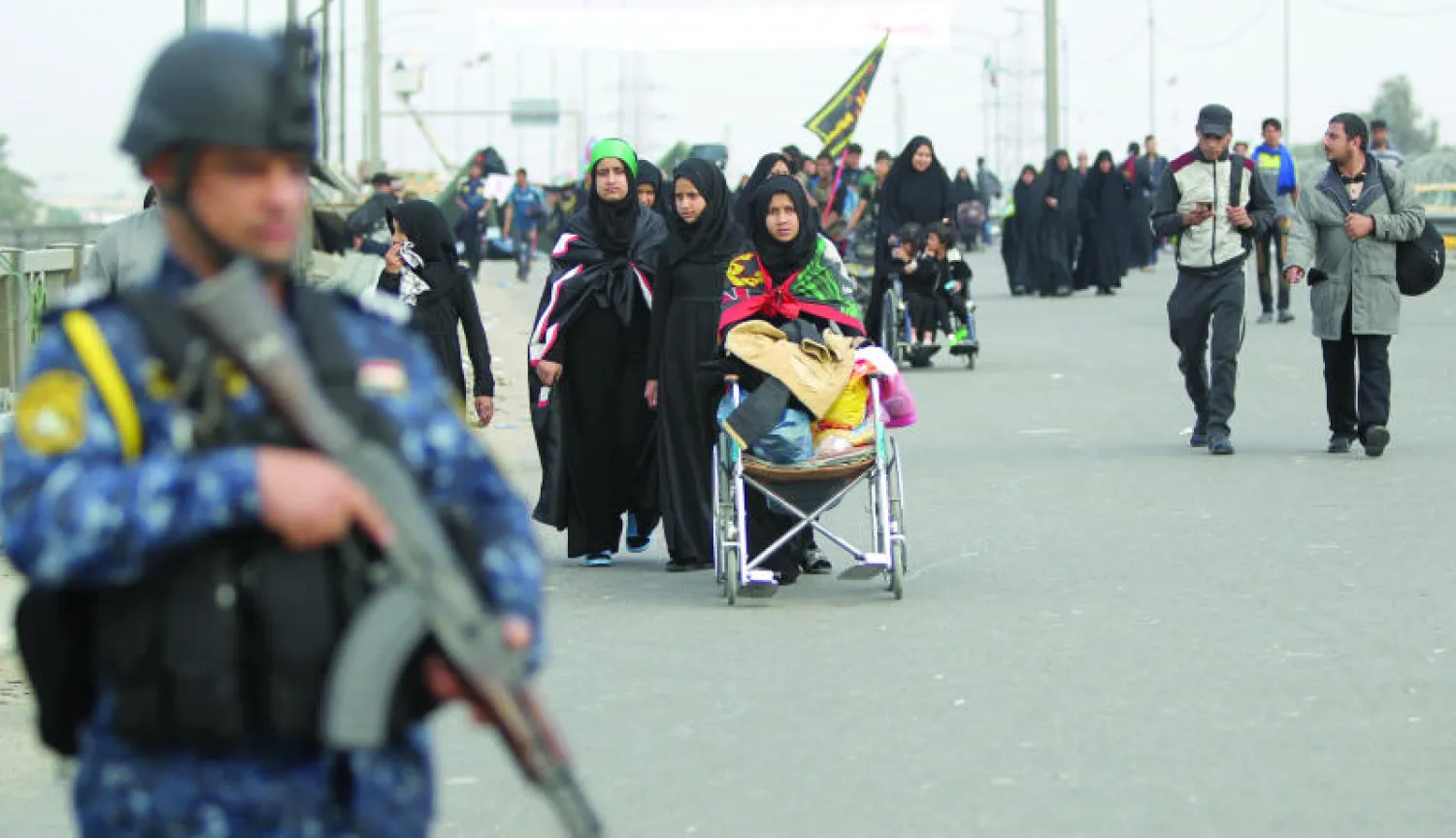 زوار «الأربعينية» المتوجهون إلى كربلاء يمرون بحي الدورة ببغداد تحت مواكبة قوات أمنية عراقية أمس (أ.ف.ب)