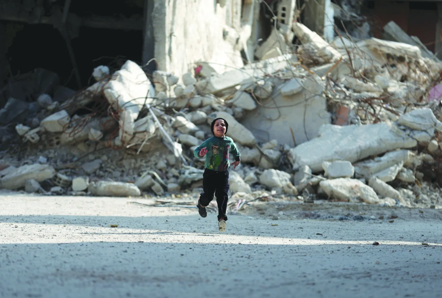 صبي من مدينة دوما بريف دمشق يركض عبر الأبنية المدمرة بفعل قصف قوات الأسد (رويترز)