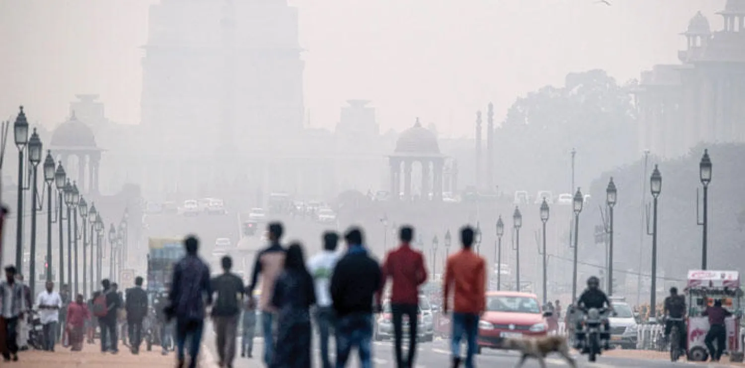 مشاة يتجولون قرب مبان حكومية لفها الدخان المضبب في نيودلهي عاصمة الهند (ا ف ب)