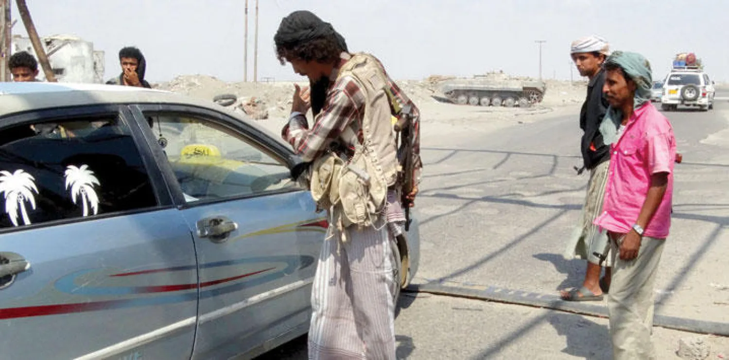 عضو في اللجنة الشعبية  المؤيدة للحكومة اليمنية يستوقف إحدى السيارات بمنطقة تفتيش في محافظة أبين (رويترز)