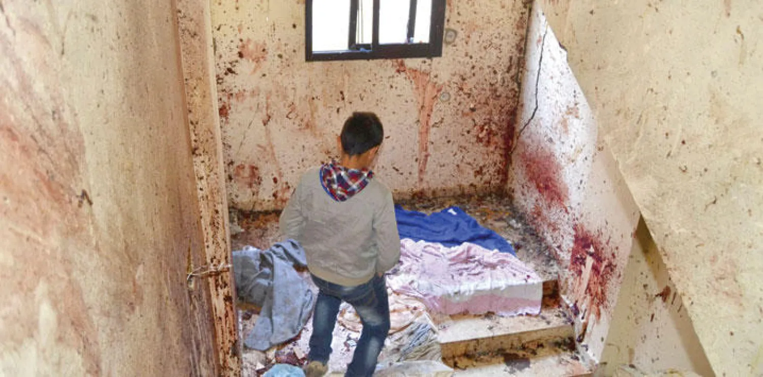 صبي على درج المبنى الملطخة جدرانه بالدماء، حيث فجر الانتحاري محمد حمزة نفسه في بلدة دير عمار، القريبة من مدينة طرابلس عاصمة شمال لبنان  (رويترز)
