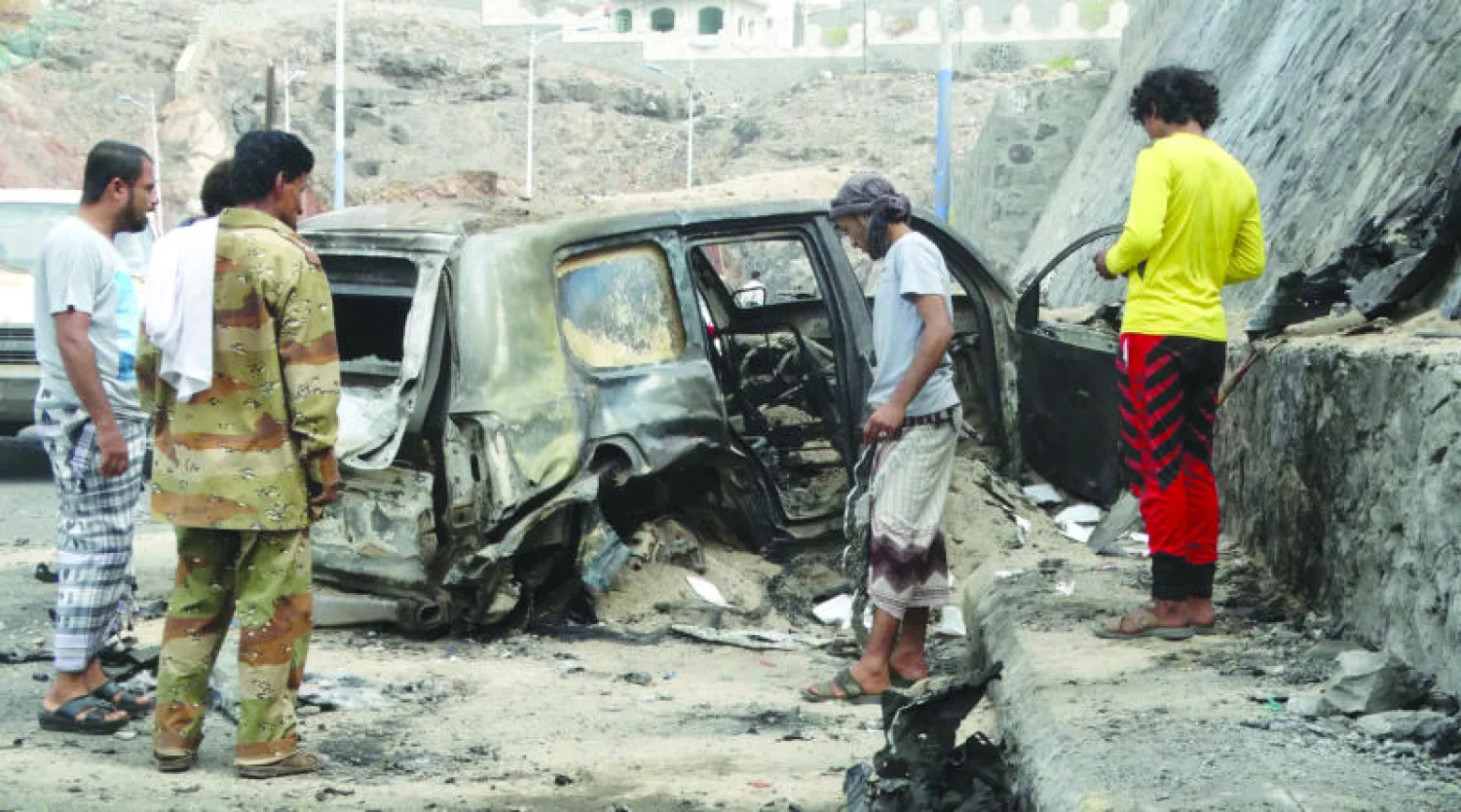 يمنيون يعاينون آثار الهجوم الانتحاري الذي استهدف موكب محافظ عدن جعفر محمد سعد أمس في مديرية التواهي (رويترز)