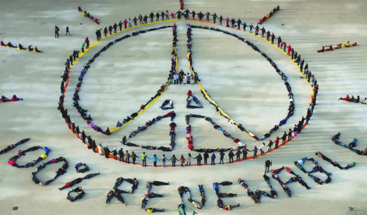 أشخاص يمثّلون رمز «صلِّ من أجل باريس» مع تعليق «طاقات متجددة 100 في المائة» قرب برج إيفل في باريس أمس (أ.ف.ب)