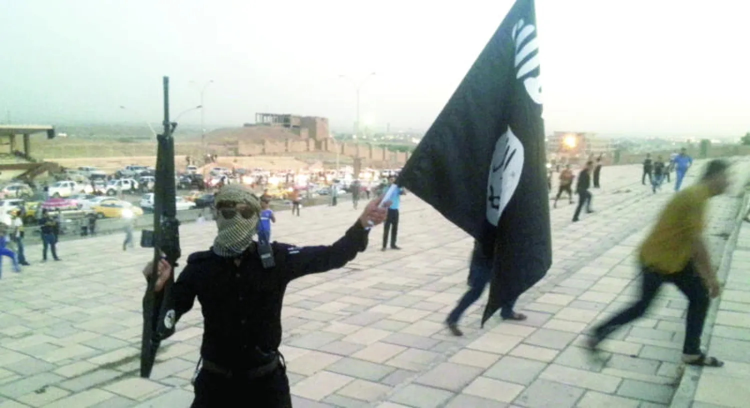 مقاتل من «داعش» يرفع راية التنظيم بيد وسلاحه باليد الأخرى في الموصل (رويترز)