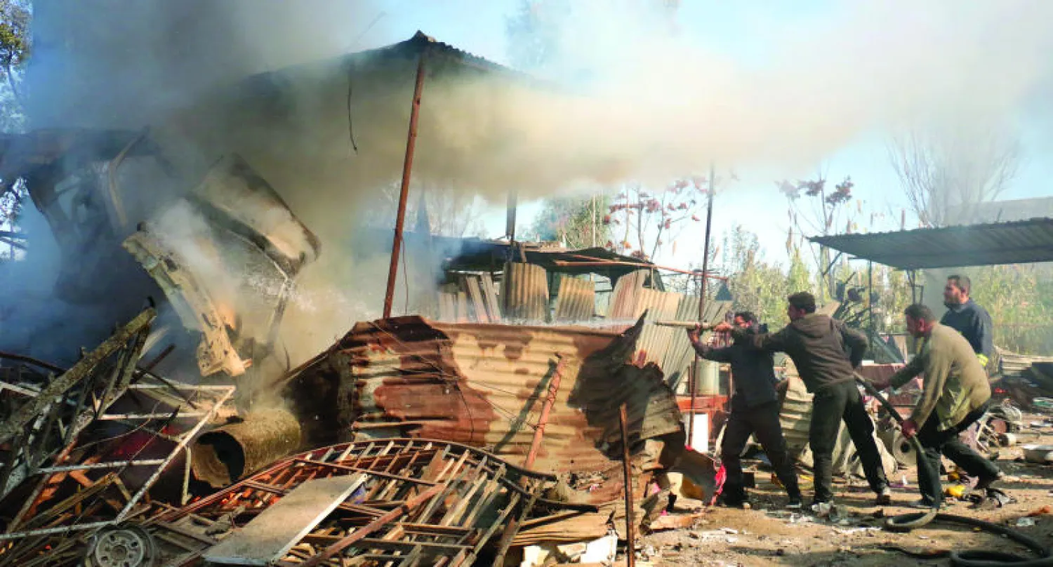 سوريون يحاولون إخماد حريق أشعلته غارة جوية لطائرات النظام في الغوطة الشرقية أمس (غيتي)