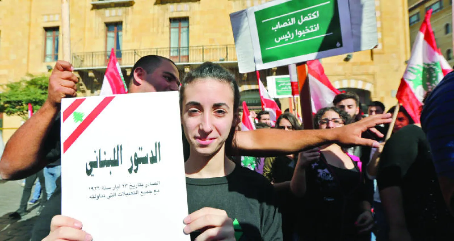 صورة تعود الى نوفمبر الماضي لمتظاهرين لبنانيين يحمل احدهم الدستور اللبناني في بيروت (إ.ب.أ)