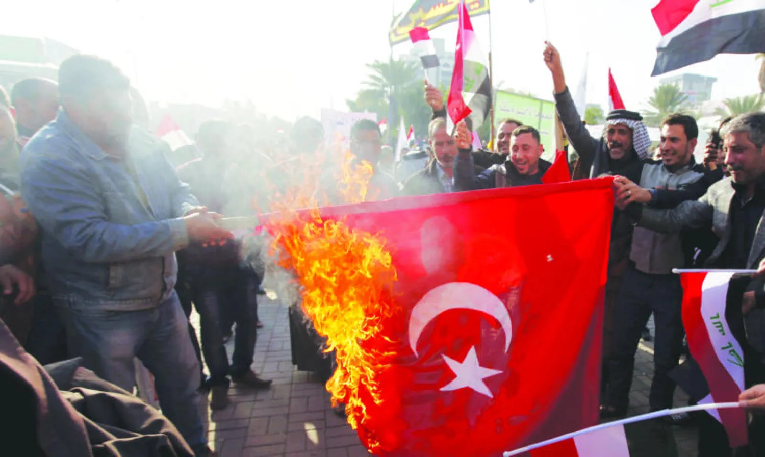 عراقيون يحرقون العلم التركي في ساحة التحرير بوسط بغداد احتجاجا على التدخل العسكري التركي بالعراق (رويترز)