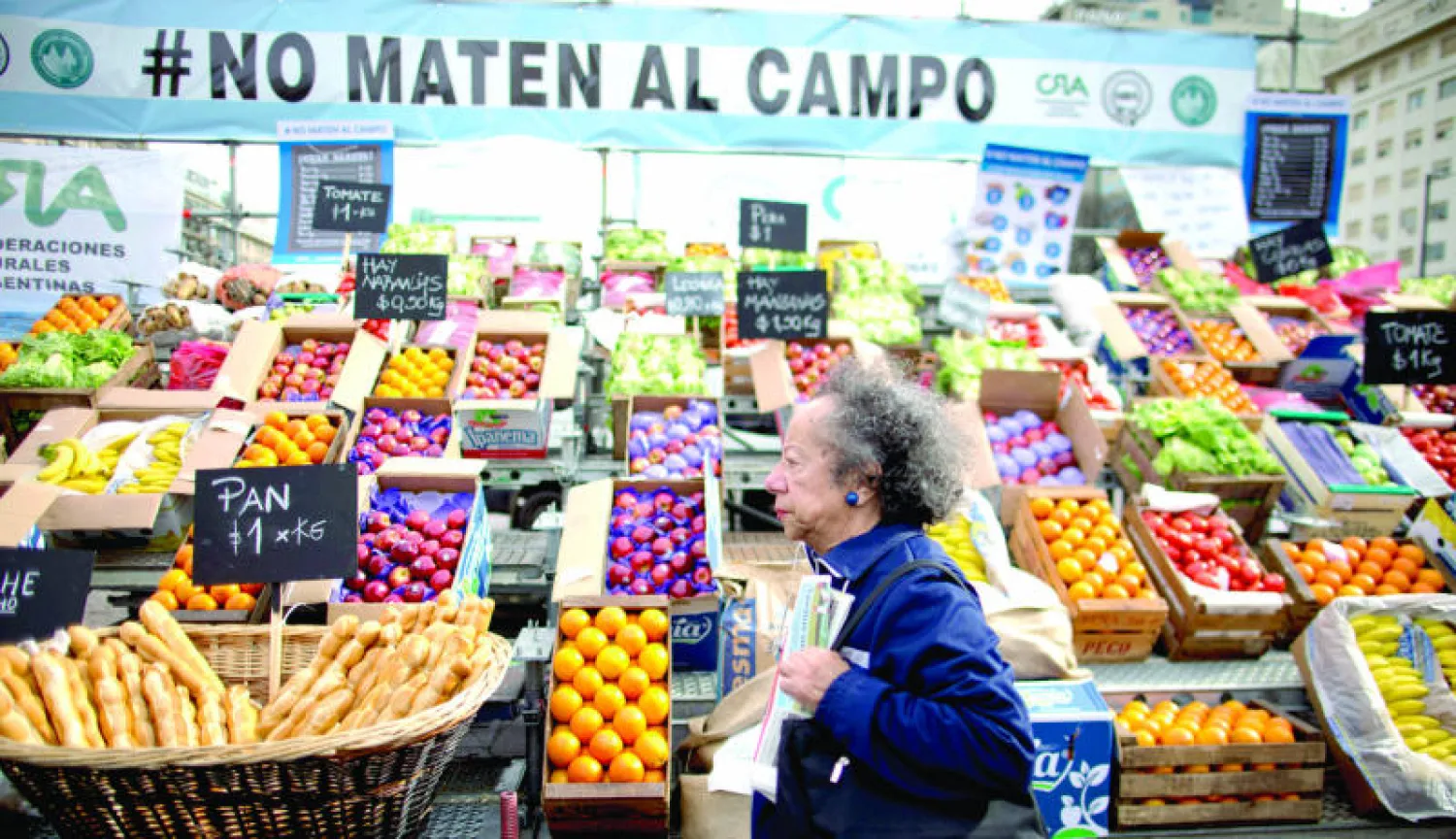 أرجنتينية تمر أمام متجر للخضر يحمل لافتة كتب عليها (لا تقتلوا الحقول) بمناسبة احتجاج المزارعين في بوينس آيرس أمس (أ.ب)