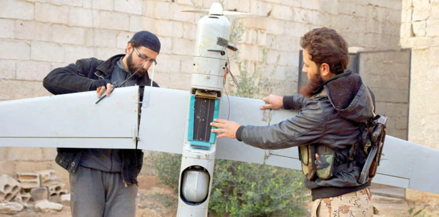 مقاتلان من «حركة المثنى» الإسلامية في درعا يتفحصان طائرة استطلاع روسية قالت الحركة إنها أسقطتها في الشيخ مسكين جنوب سوريا (رويترز)