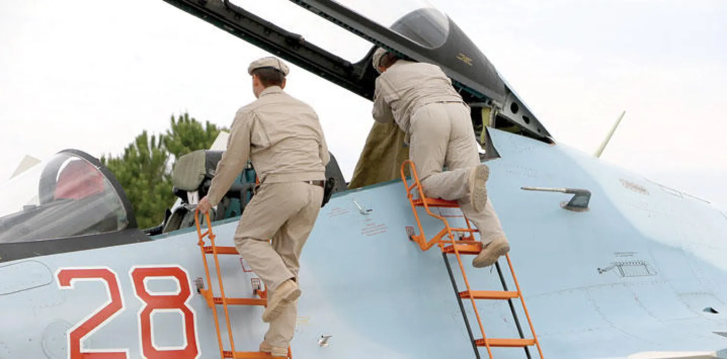 تقنيون روس يجهزون طائرة «سو - 30 إس إم» المقاتلة قبل انطلاقها من مطار حميميم العسكري في اللاذقية بسوريا (إ.ب.أ)