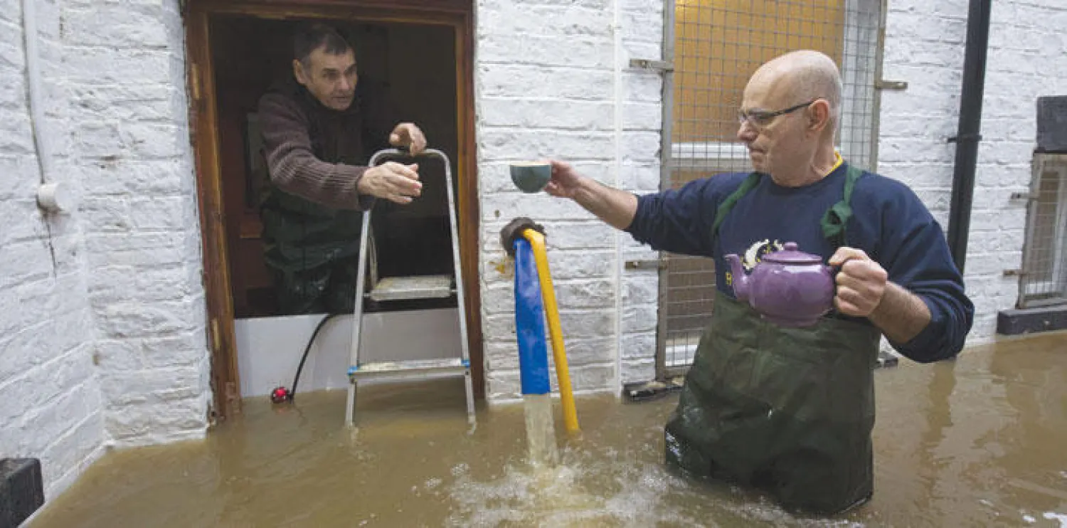 رجل يقدّم الشاي لجاره في منطقة منكوبة في يورك أمس (أ.ف.ب)