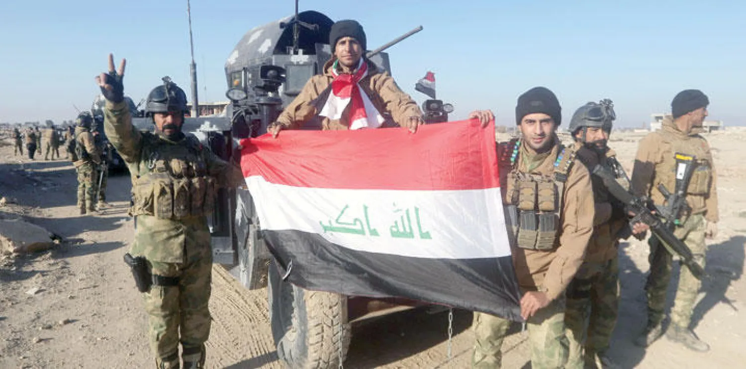 جنود في قوة مكافحة الإرهاب يرفعون العلم العراقي في إحدى مناطق الرمادي أمس (أ.ف.ب)
