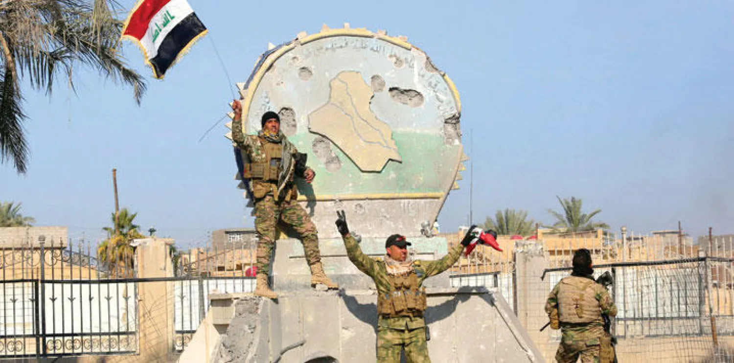 جنود من قوات الأمن العراقية يرفعون علم العراق أمام مبنى حكومي في وسط مدينة الرمادي بعد تحريرها من مسلحي داعش أول من أمس (رويترز)