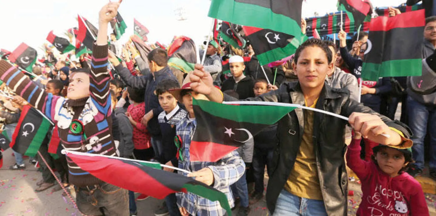 ليبيون يلوحون بأعلام بلادهم في ساحة الشهداء بطرابلس احتفالا بعيد الاستقلال (أ.ف.ب)
