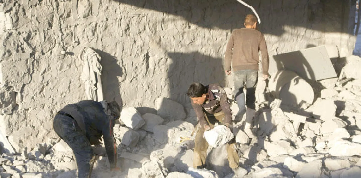 بعض المواطنين والحركيين المحليين يتفقدون الأضرار التي لحقت بمنازل بلدة خان السبيل في ريف محافظة إدلب بشمال غربي سوريا بعد غارة قصف جوي شنها الطيران الحربي الروسي على المنطقة (رويترز)