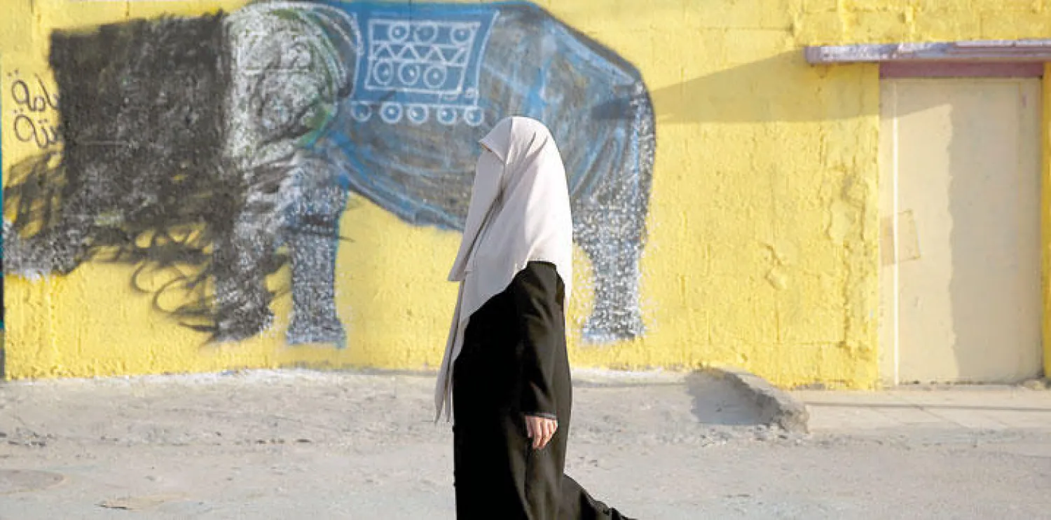 فلسطينية تسير في مخيم شاتي للاجئين بقطاع غزة (أ.ب)