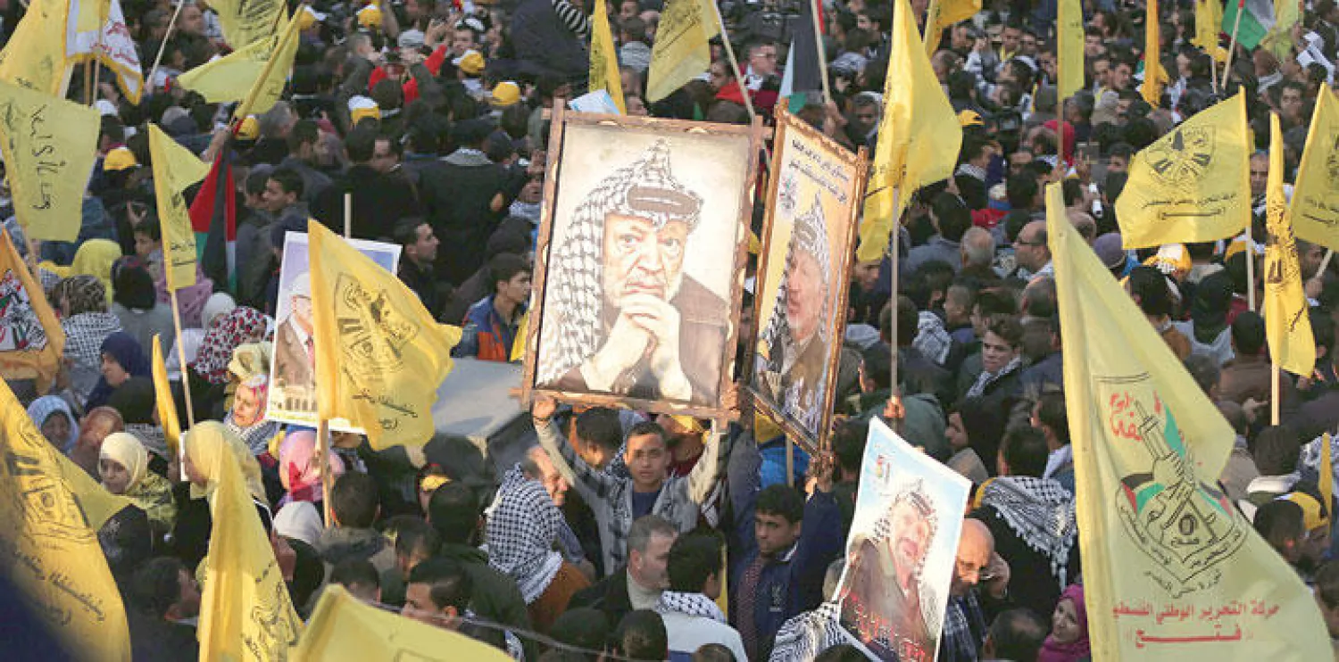 فلسطينيون مؤيدون لحركة فتح يحملون لافتات وصور الزعيم الراحل ياسر عرفات في شوارع غزة بمناسبة الاحتفال بالذكرى ال 51 لتأسيس حركة فتح (إ.ب.أ)