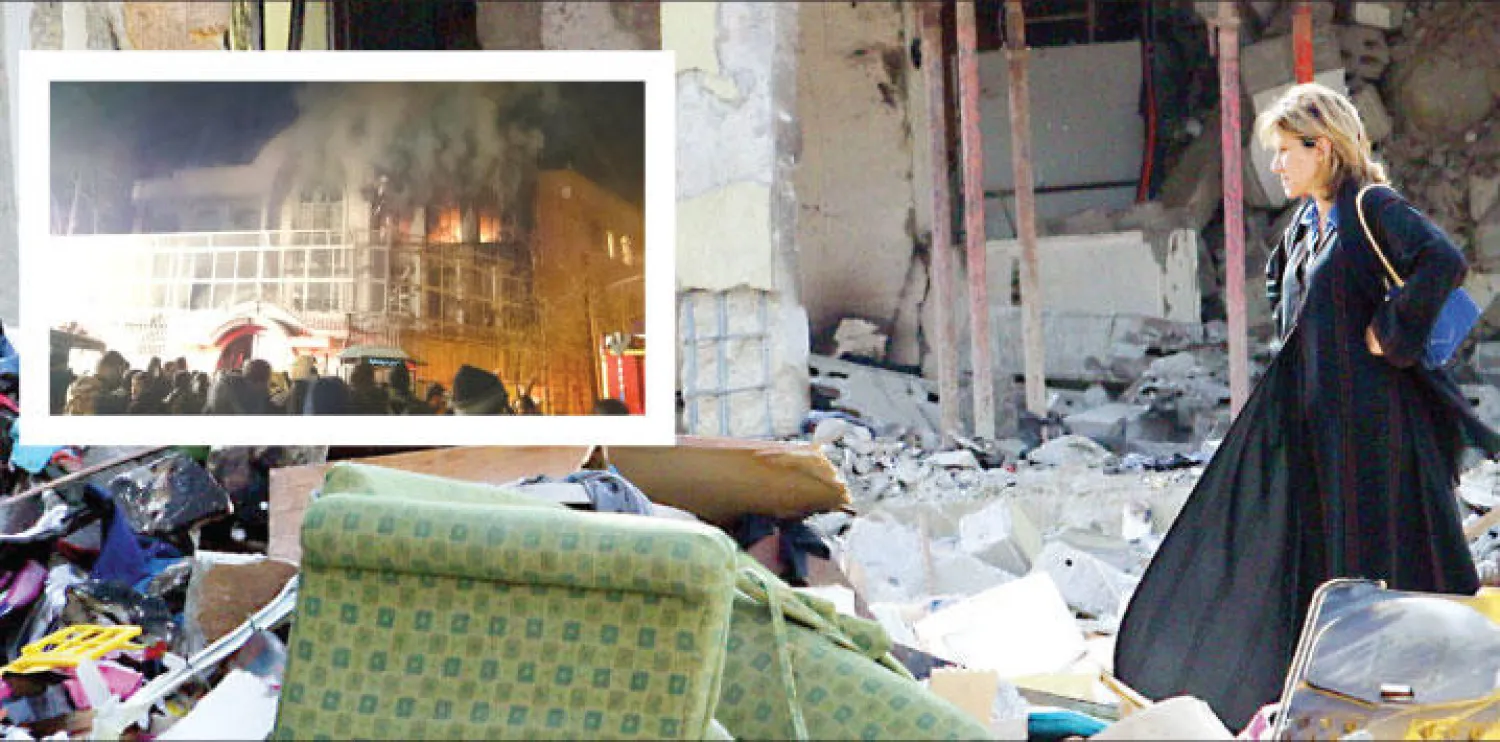 مقيمة تعاين الدمار الذي خلفه الارهابيون في مجمع المحيا بالرياض في 8 نوفمبر 2003 .. وفي الاطار أعمدة الدخان والسنة النيران تتصاعد في السفارة السعودية بطهران أمس ({الشرق الأوسط})