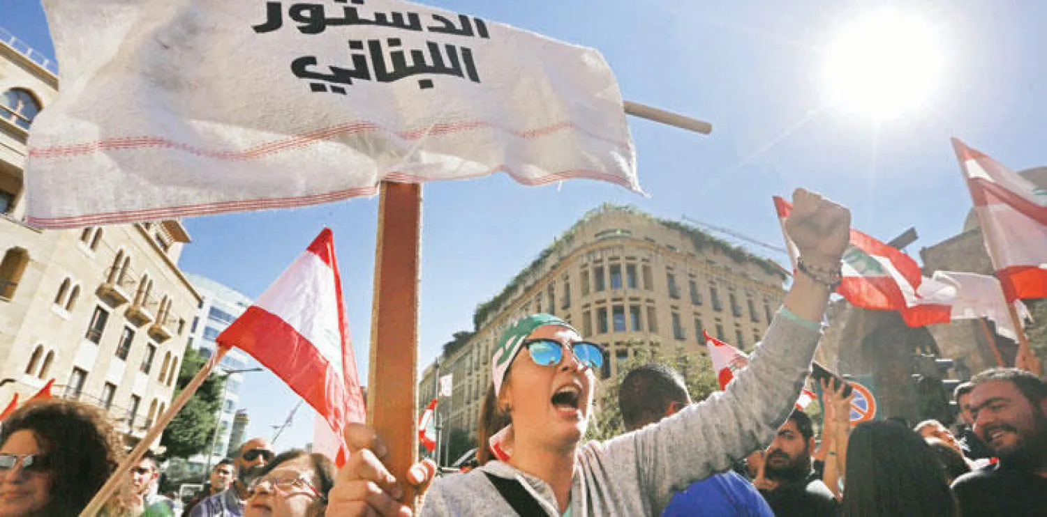 لبنانية ترفع لافتة لمطالبة البرلمان بتفعيل الدستور اللبناني وانتخاب رئيس جديد للبلاد أمام مقر البرلمان في بيروت (أ.ب)
