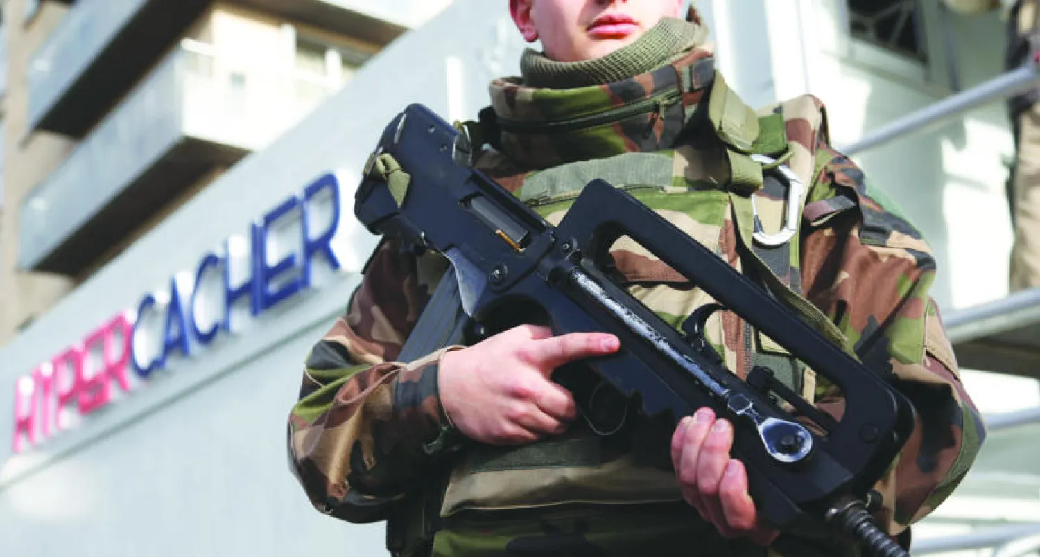 جندي فرنسي أمام المتجر اليهودي الذي تعرض لهجمات من أحمدي كوليبالي عقب ساعات من الاعتداء على مجلة «شارلي إيبدو» في العاصمة باريس الذي يوافق غدا الذكرى الأولى للهجمات («الشرق الأوسط»)