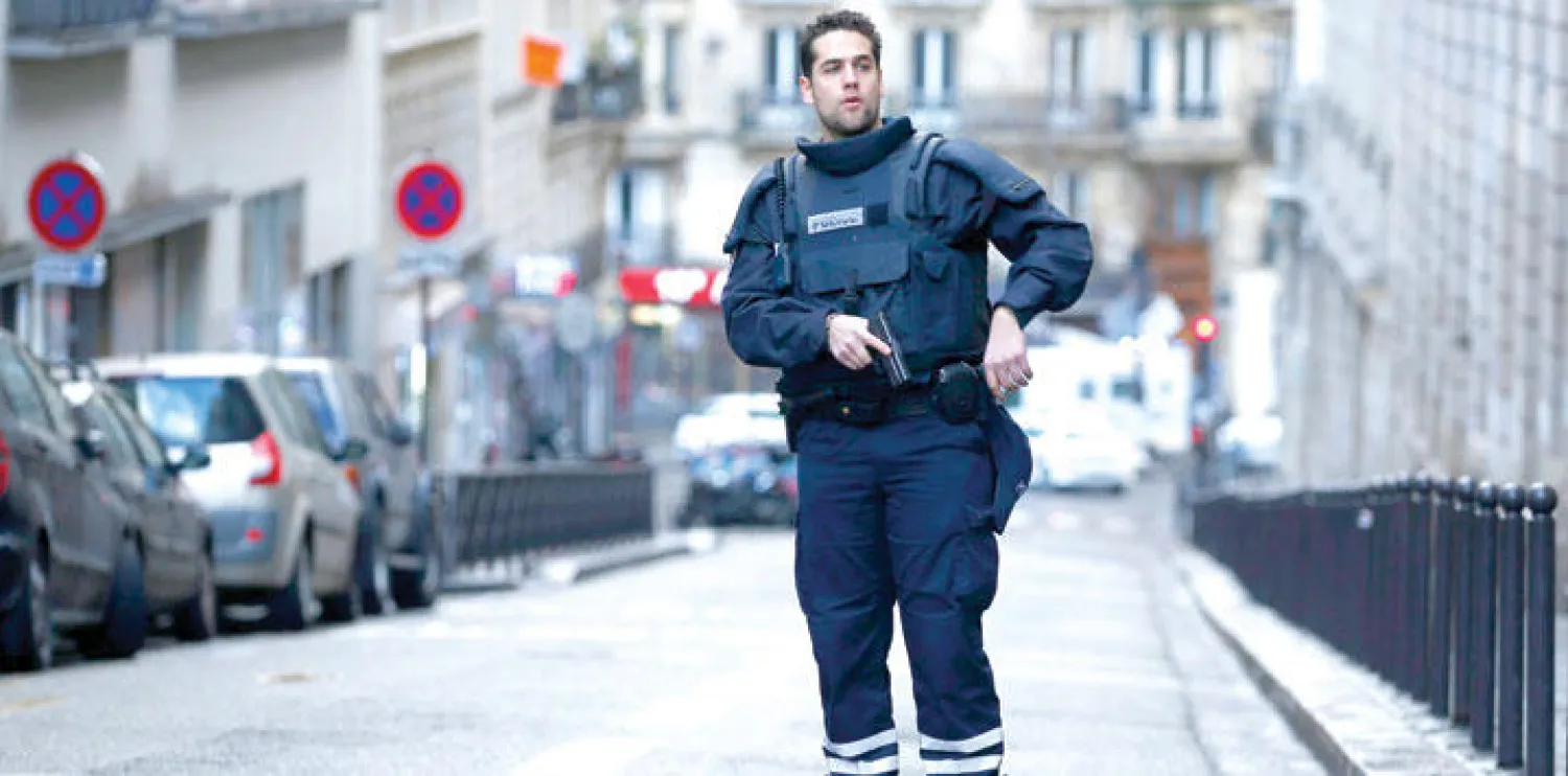 شرطي يراقب الموقف أمام الموقع الذي قُتل فيه رجل مسلح بساطور أراد اقتحام مركز شرطة في باريس أمس (إ.ب.أ)