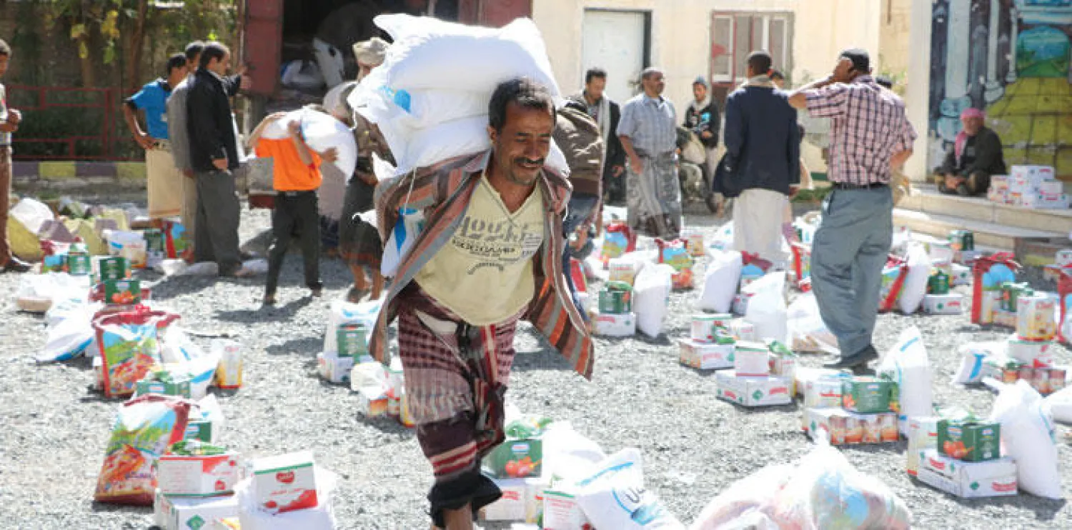 يمنيون ينقلون أمس أكياس محملة بمساعدات غذائية قدمتها إحدى المنظمات الإغاثية لمهجري مدنية إب اليمنية (غيتي)