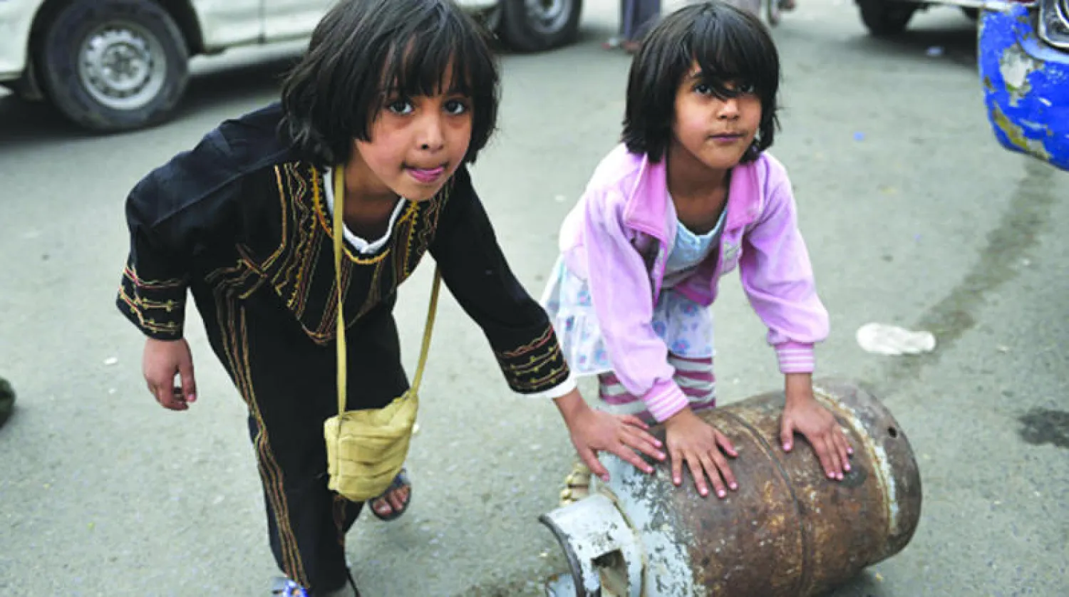 طفلتان يمنيتان تدحرجان أسطوانة غاز بصنعاء التي تعاني من عدة أزمات بسبب الحصار الحوثي للعاصمة (غيتي)