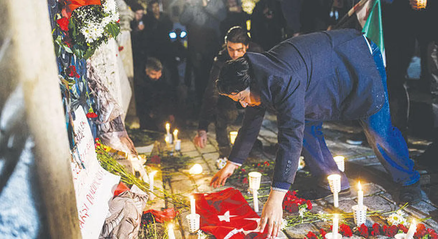 سوري يضع علماً تركياً إلى جانب ورود وشموع تكريماً لأرواح ضحايا تفجير إسطنبول الدامي أمس (أ.ف.ب)