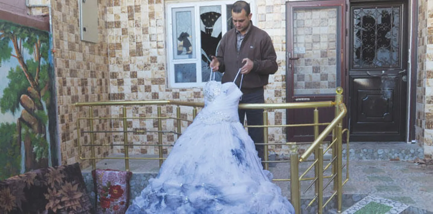 التركماني أحمد حسن مجيد يعرض فستان العرس الوحيد الذي بقي من بضاعتهالتي أتلفت باستهداف متجره خلال مواجهات طوزخورماتو (أ.ف.ب)