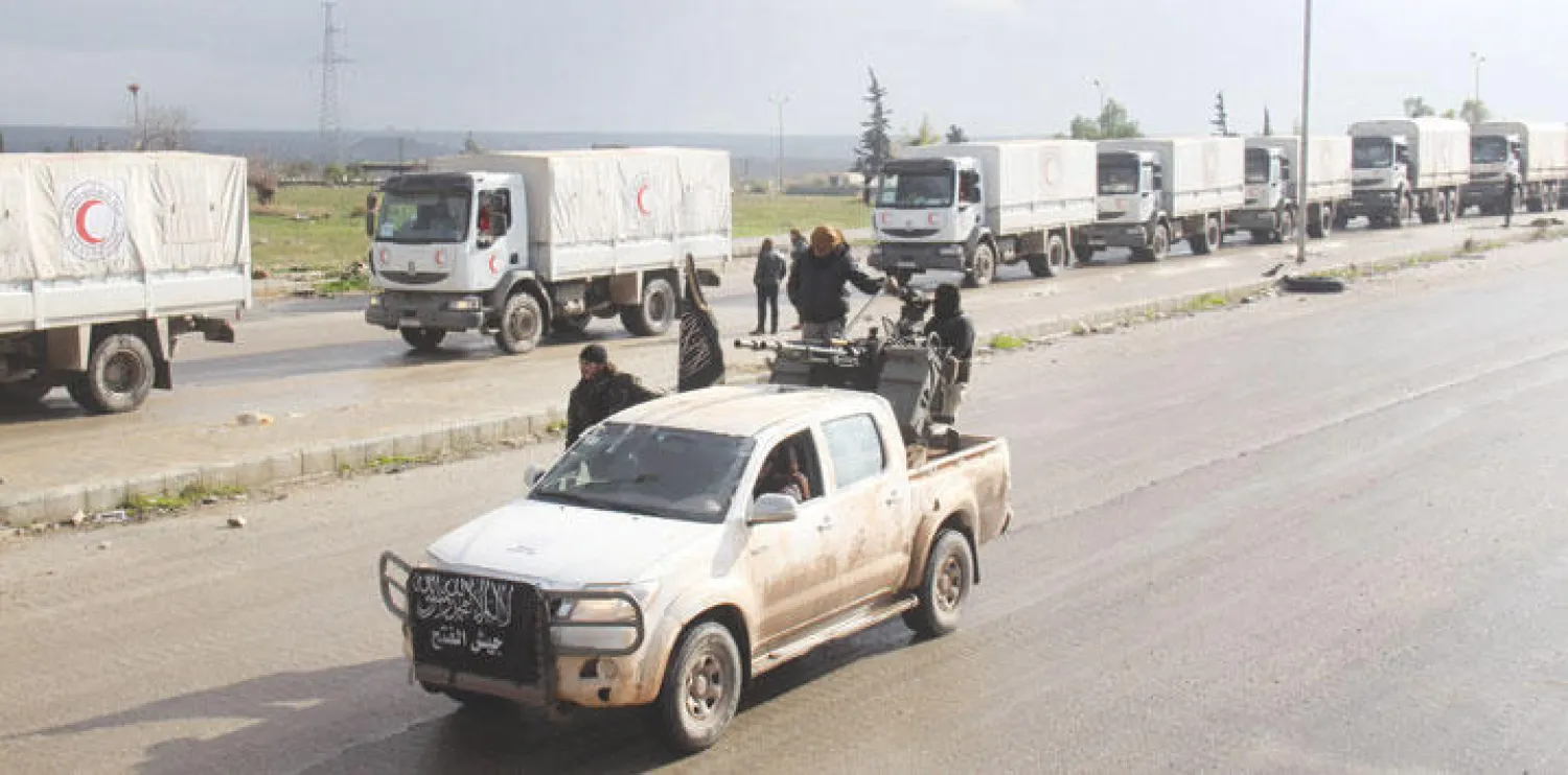 عناصر من جيش الفتح يواكبون قافلة مساعدات للهلال الأحمر السوري إلى بلدتي كفريا والفوعة المحاصرتين في ريف إدلب أمس (أ.ف.ب.)