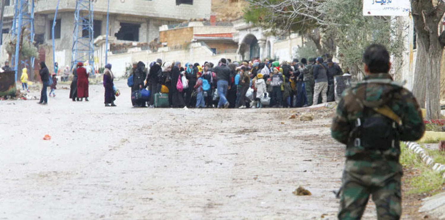 أحد جنود النظام السوري يراقب سكانا من مضايا يحاولون الفرار أمس من الحصار (رويترز)