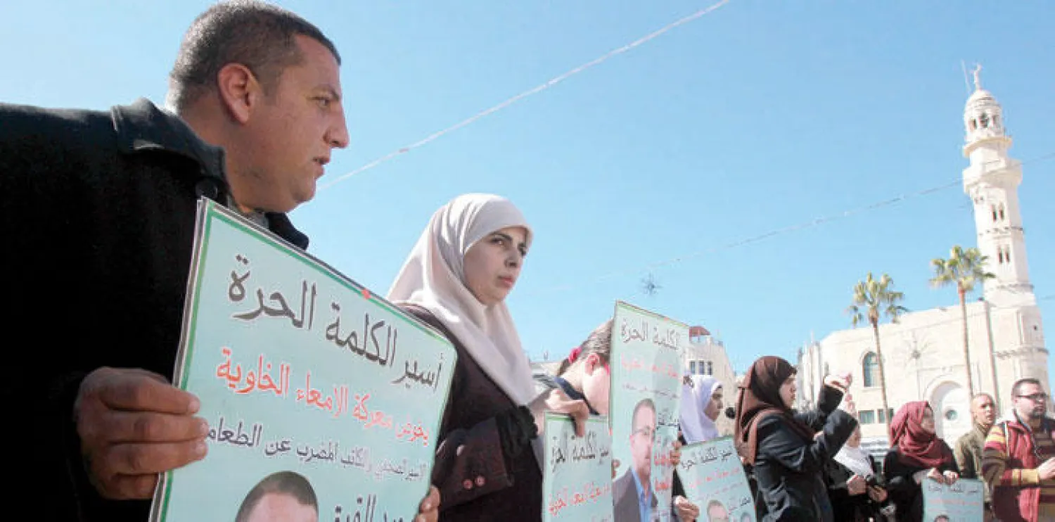 زوجة الصحافي الفلسطيني محمد القيق المضرب عن الطعام في السجون الإسرائيلية، وشقيقه أثناء مظاهرة في بيت لحم بالضفة الغربية أمس للمطالبة بإطلاق سراحه (أ.ف.ب)