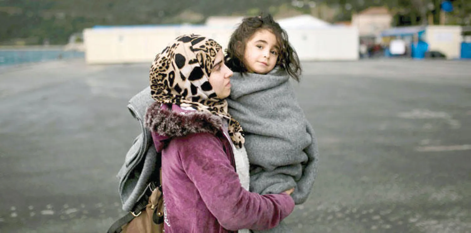 لاجئة سورية تحمل طفلتها بجزيرة ساموس اليونانية(أ.ف.ب)