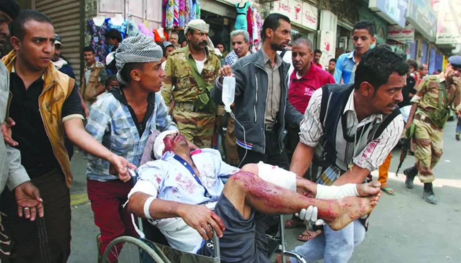 يمنيون يحاولون إنقاذ يمني أصيب جراء قصف للحوثيين على أحد الأحياء الشعبية بمدينة تعز أمس (رويترز)