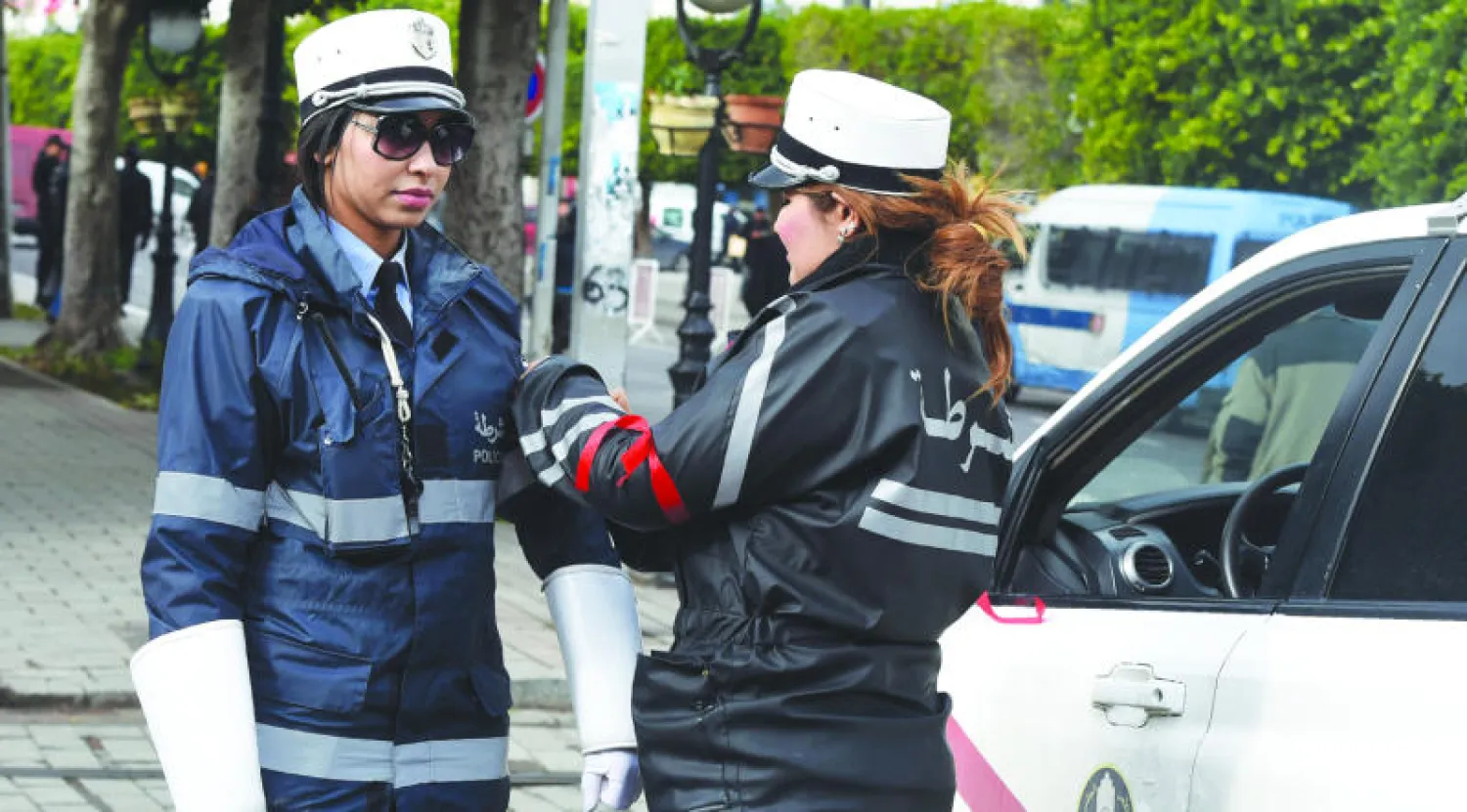 شرطيتان تونسيتان تضعان شريطاً أحمر على ذراعيهما في العاصمة أمس احتجاجا على قلة الرواتب وصعوبة ظروف العمل (أ.ف.ب)