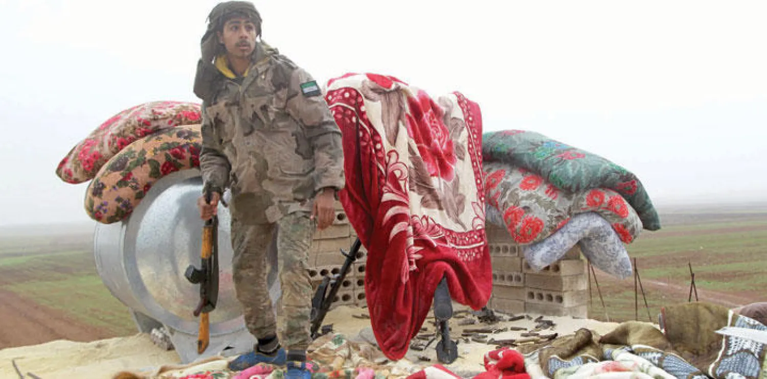 مقاتل من لواء السلطان مراد التابع للجيش السوري الحر يتطلع إلى نقطة استهداف سلاحه إلى مناطق «داعش» في ريف حلب الشمالي (رويترز)